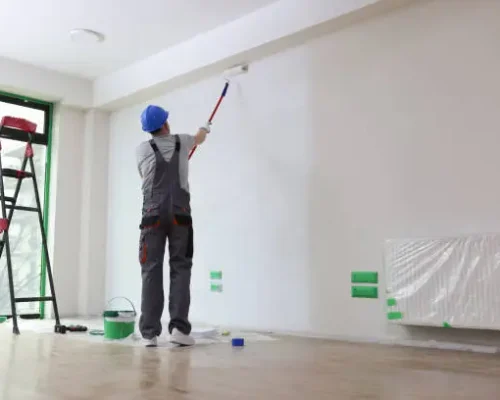 Professional painter paints office wall with roller brush. Decoration and improvement office interior concept.